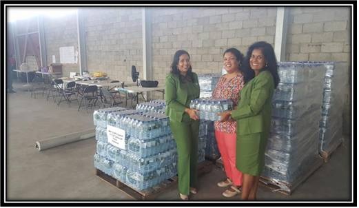 Ms. Elena Villafana-Sylvester (CEO, F.E.E.L Organization) happily accepts 300 cases of water for our Caribbean neighbours from SAPH Representatives